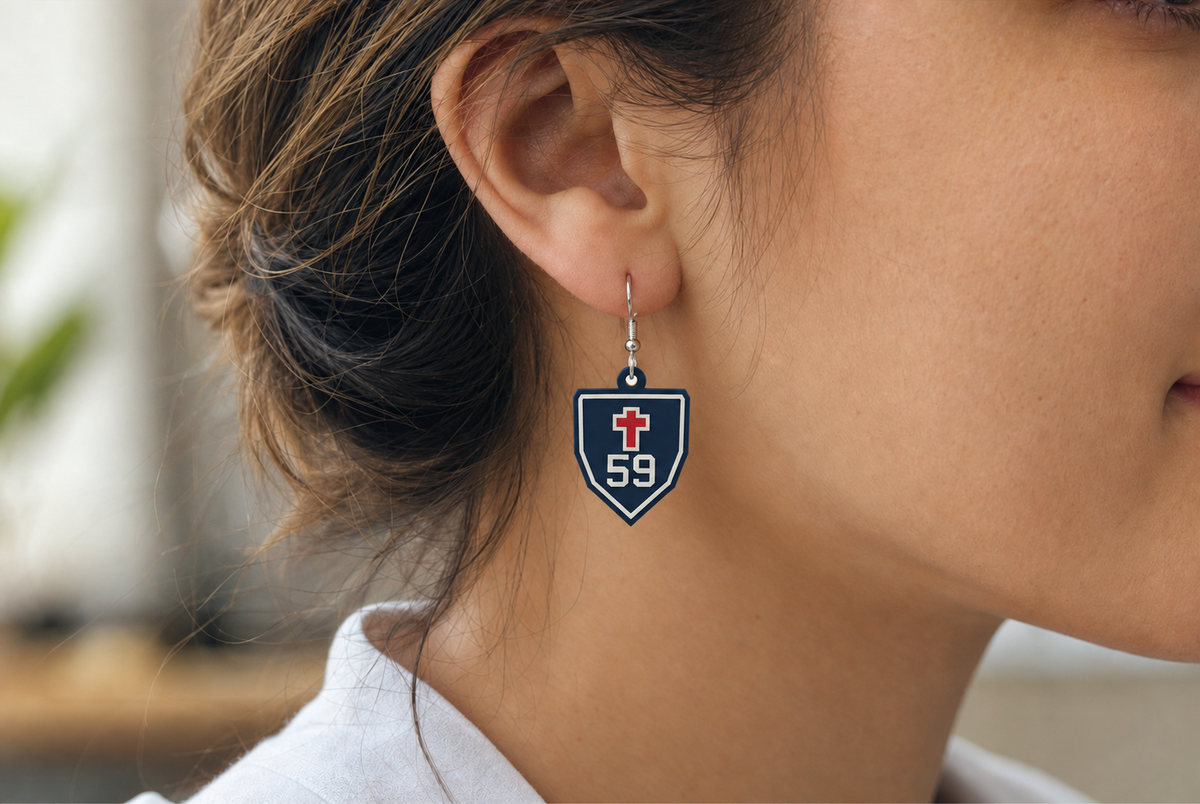 AI-generated styling mockup: Christ Prep shield cross-and-number earring, shown with example number 59