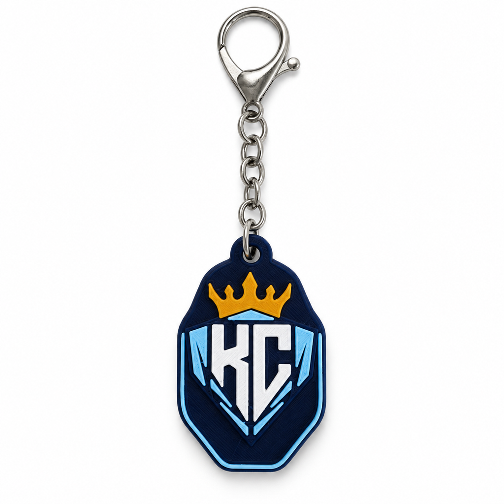 KC Diamonds shield keychain with a gold crown, white KC lettering, light-blue details, and a silver-colored clasp and short chain on a white background